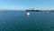 aerial footage of the rippling blue waters of Long Beach Harbor with boats sailing, the Queen Mary, lush green palm trees