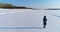 Aerial footage of running woman in winter landscape of a frozen river with a forest and a view of the city with