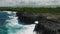 Aerial footage of surge of waves at a rocky coast with clear blue water