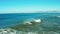 Aerial footage of unrecognizable surfer catching ocean wave on longboard