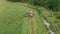 Aerial: forage harvester removes green grass for silage or haylage in a tractor trailer near the forest