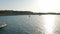 Aerial forward view of boats parked in a silent and calm sea surrounded by mountain and greenery at sunset in Ibiza in