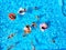 Aerial of friends having party in swimming pool with inflatable flamingo, swan, mattress. Happy young people relax at