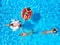 Aerial of friends having party in swimming pool with inflatable flamingo, swan, mattress. Happy young people relax at
