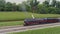 Aerial Front to Side View of a Steam Passenger Train Blowing Smoke at a Small Station Waiting For Passengers