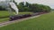 Aerial Front to Side View of a Steam Passenger Train Blowing Smoke at a Small Station Waiting For Passengers