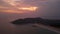 Aerial hyperlapse of vibrant sunset over coastal landscape. Ocean waves meet shoreline during dusk as skies transition