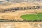 Aerial image of agricultural fields and a housing development in the background