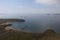 Aerial image of harbor in calm sea with alone rock in the middle and cargo ships at anchor. Nakhodka, Russia