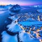 Aerial image of a winter sunset showing a blue snow capped a a a and a Hamnoy in the Norwegian Lofoten vistas in all