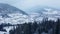 Aerial of inhabited locality in the mountains on winter. Mountain village buildings and houses on snowy hill slopes