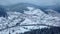 Aerial of inhabited locality in the mountains on winter. Mountain village buildings and houses on snowy hill slopes