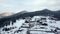 Aerial of inhabited locality in the mountains on winter. Mountain village buildings and houses on snowy hill slopes