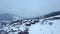 Aerial of inhabited locality in the mountains on winter. Mountain village buildings and houses on snowy hill slopes