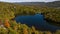 Aerial of a lake in upstate New York during the colorful fall foliage on a sunny day.