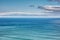 Aerial, landscape, and copyspace view of the ocean and beach waves against a cloudy climate and blue sky in summer