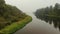 Aerial landscape of a misty river between jungles of green trees reflected in the water