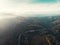 Aerial landscape panorama of morning sun and haze above beautiful mountains with curve road