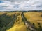 Aerial landscape of rural road among yellow rolling hills in Australian countryside.