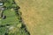 Aerial landscape view of village houses and distant green cultivated agricultural fields with growing crops on bright