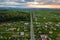 Aerial landscape view of village houses and distant green cultivated agricultural fields with growing crops on bright