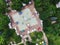 Aerial of a large pool surrounded by trees with colored tents pitched on the concrete surrounding the pool