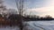 Aerial lateral flying with a drone crossing naked trees and showing the banks of the frozen river in winter at Berges-des-quatre-