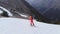 An aerial-looking skier in an orange suit makes a kicker jump in the spring when there is little snow in the evening