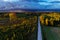 Aerial of lush wild boreal forest and a road during colorful autumn foliage in Estonian nature.