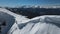 Aerial: a man skiing along a ridge in winter with white mountains