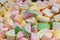 Aerial marshmallows in the shape of a watermelon slice pink yellow green, close-up background wallpaper. Sweet candy marmalade in