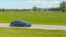 AERIAL: Modern tourists speed through the countryside in a brand new Tesla 3