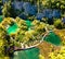 Aerial morning wiew of Plitvice National Park. Colorful spring scene of turists walking on the bridge in green forest with lakes