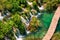 Aerial morning wiew of Plitvice National Park. Colorful spring scene of turists walking on the bridge in green forest with lakes