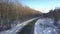 Aerial motion above empty road among naked winter wood