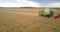 Aerial motion above operating harvester in gold wheat field