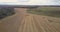 Aerial motion above wheat field with harvesting combines