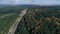 Aerial motion above wide forest crossed by empty track