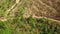 Aerial: Motocross rider driving bike on a dirt pathway going up to mountain.