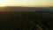 Aerial mountain sunrise view against golden morning sky green trees road scene