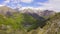 Aerial mountain view of valley, snow capped mountain, green forest on the slope. Blue sky with clouds