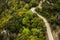 Aerial nature landscape photography of paved curved narrow pilgrim road path way in highland mountain woodland nature scenic