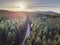 Aerial nature scenic landscape of pine trees and driving road in summer. Top view of dark green forest in mountain at sunset