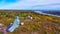 Aerial of an old farm nestled in a fall colored forest near a town harbor and river