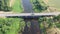 Aerial orbiting shot of truck driving over bridge. River flowing under bridge