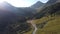 Aerial over gravel road with jeep driving through large valley in the Colorado mountains