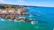 Aerial over ocean with rocky Maine coastline covered in homes