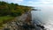 Aerial over patch of Maine coastline from above with rocky edge and green forest