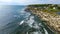 Aerial over Rocky Maine coastline with shallow waters and lighthouses in background