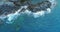Aerial overhead view of ocean mediterranean sea waves reaching and crashing on rocky shore beach coast. Sunny weather
